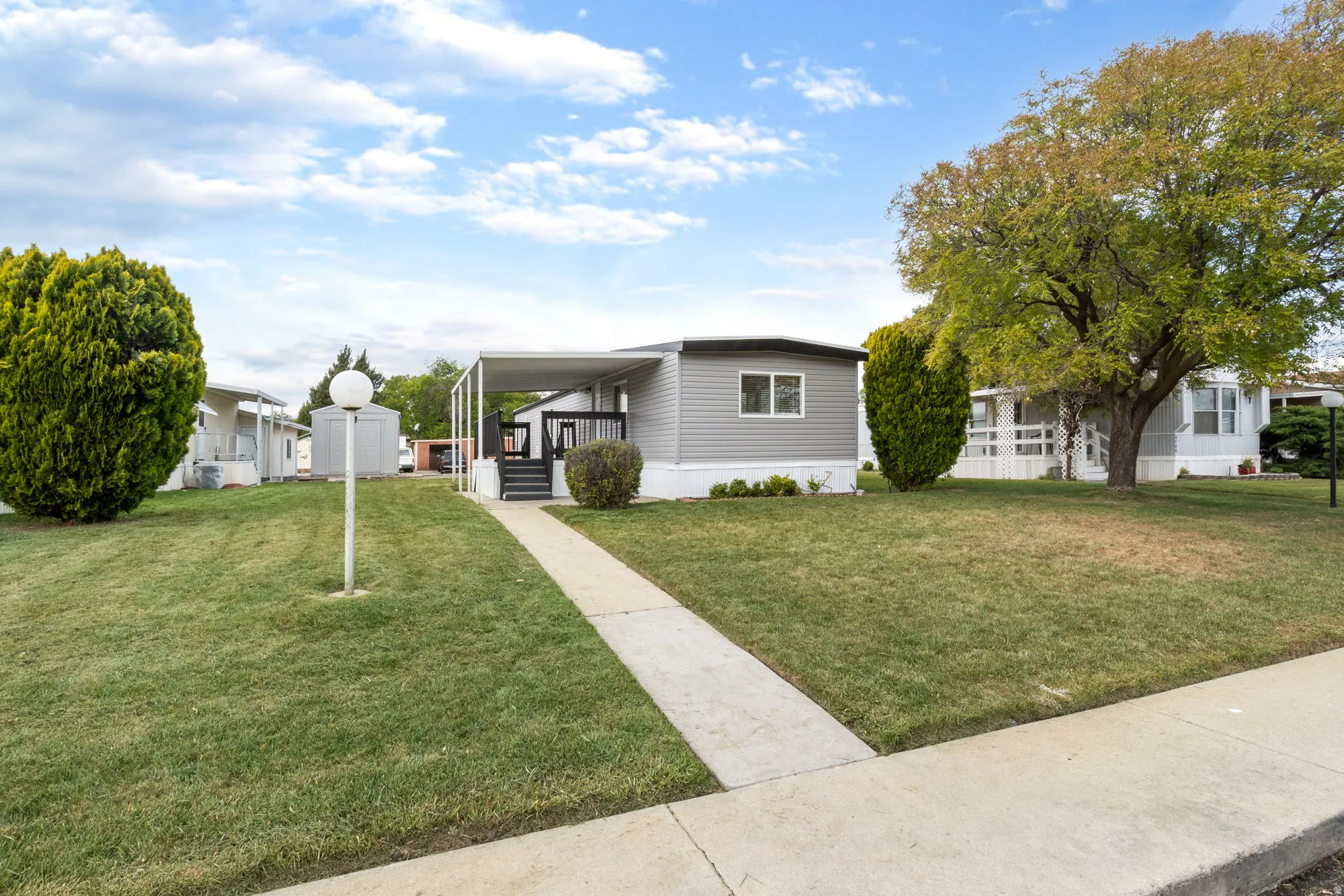Manufactured / mobile home with covered porch, a front yard, and a putting area