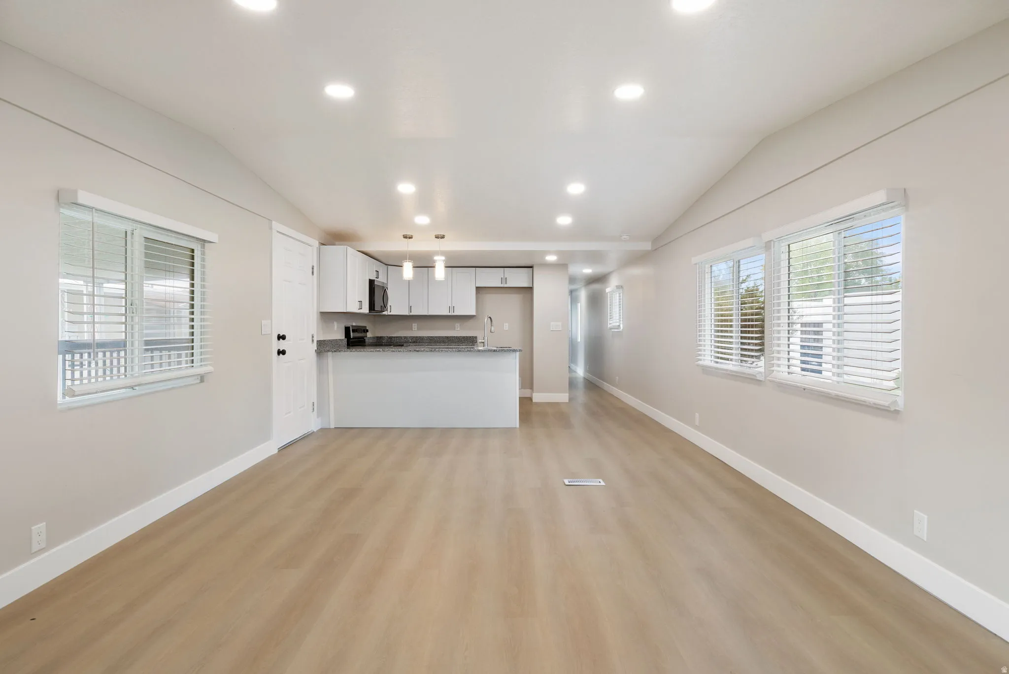 Unfurnished living room featuring vaulted ceiling, recessed lighting, and light wood-type flooring