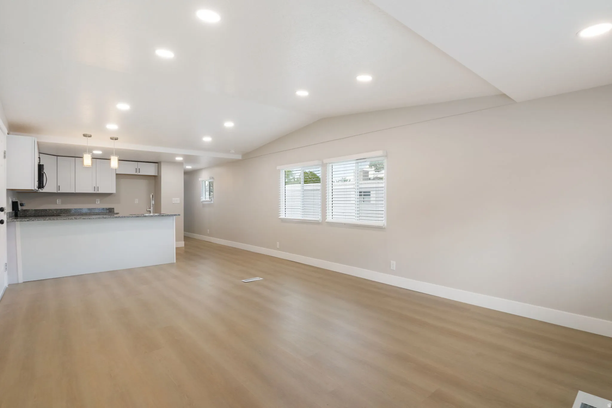 Unfurnished living room featuring recessed lighting, light wood-type flooring, and lofted ceiling