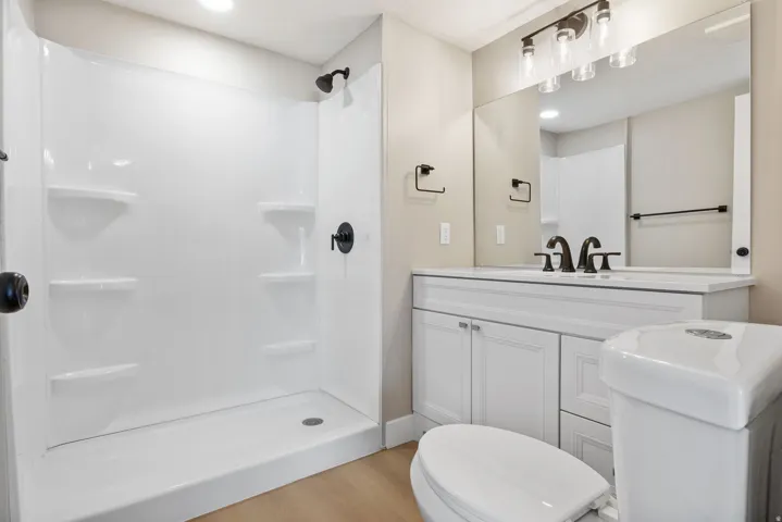 Bathroom with a stall shower, vanity, light wood-style floors, and recessed lighting