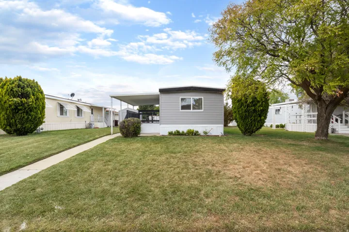 Manufactured / mobile home featuring a front lawn and an attached carport