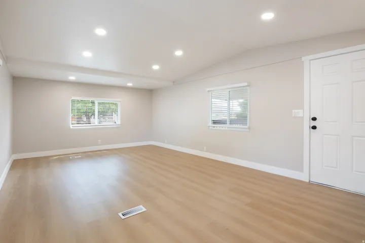 Unfurnished room with recessed lighting, light wood-style floors, lofted ceiling, and plenty of natural light