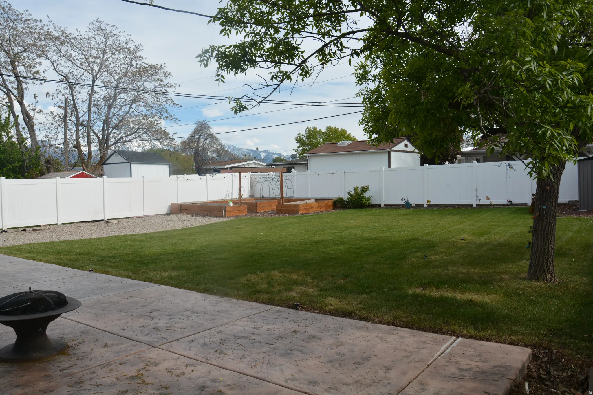 Fenced backyard with a fire pit and a vegetable garden