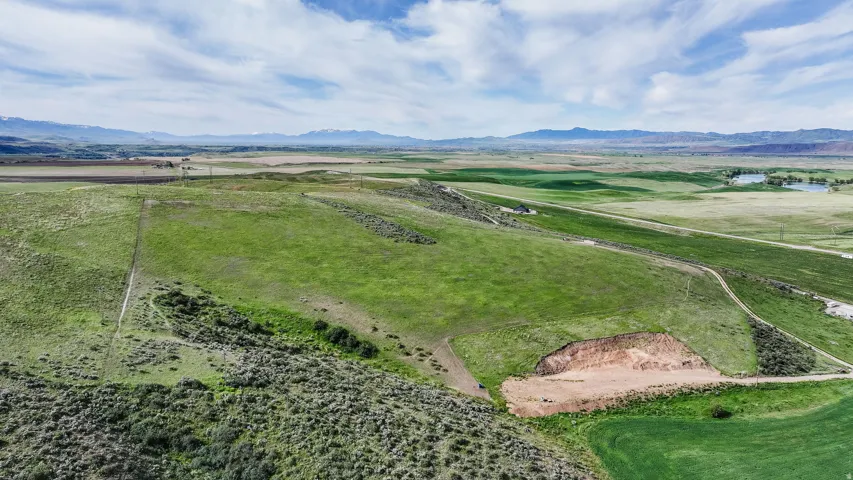 Expansive green landscape featuring rolling terrain and distant mountains