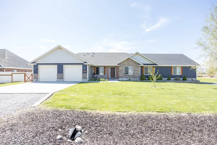 View of front of property with concrete driveway, stone siding, board and batten siding, and a garage