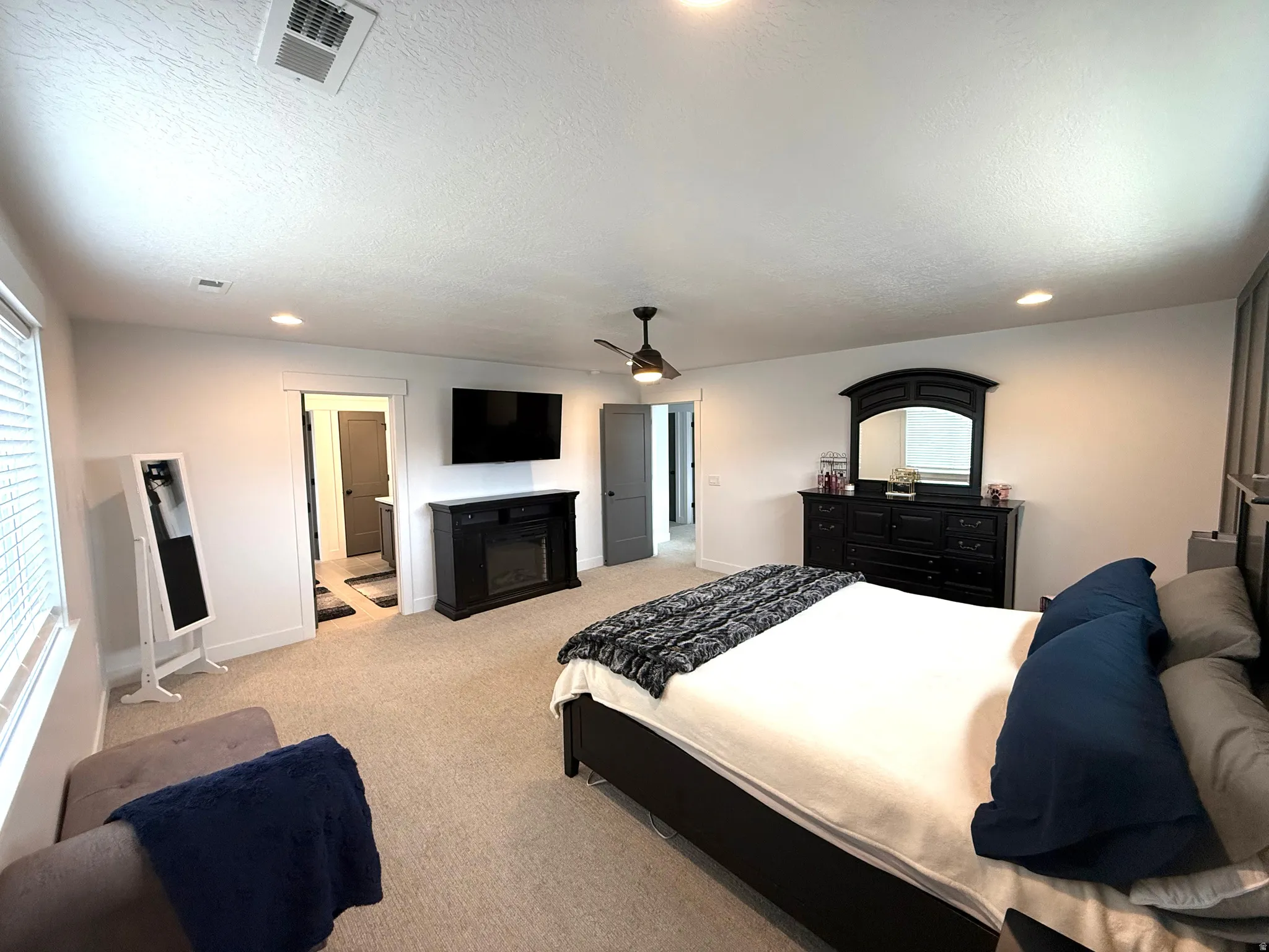 Bedroom with recessed lighting, light carpet, multiple windows, a ceiling fan, and a textured ceiling