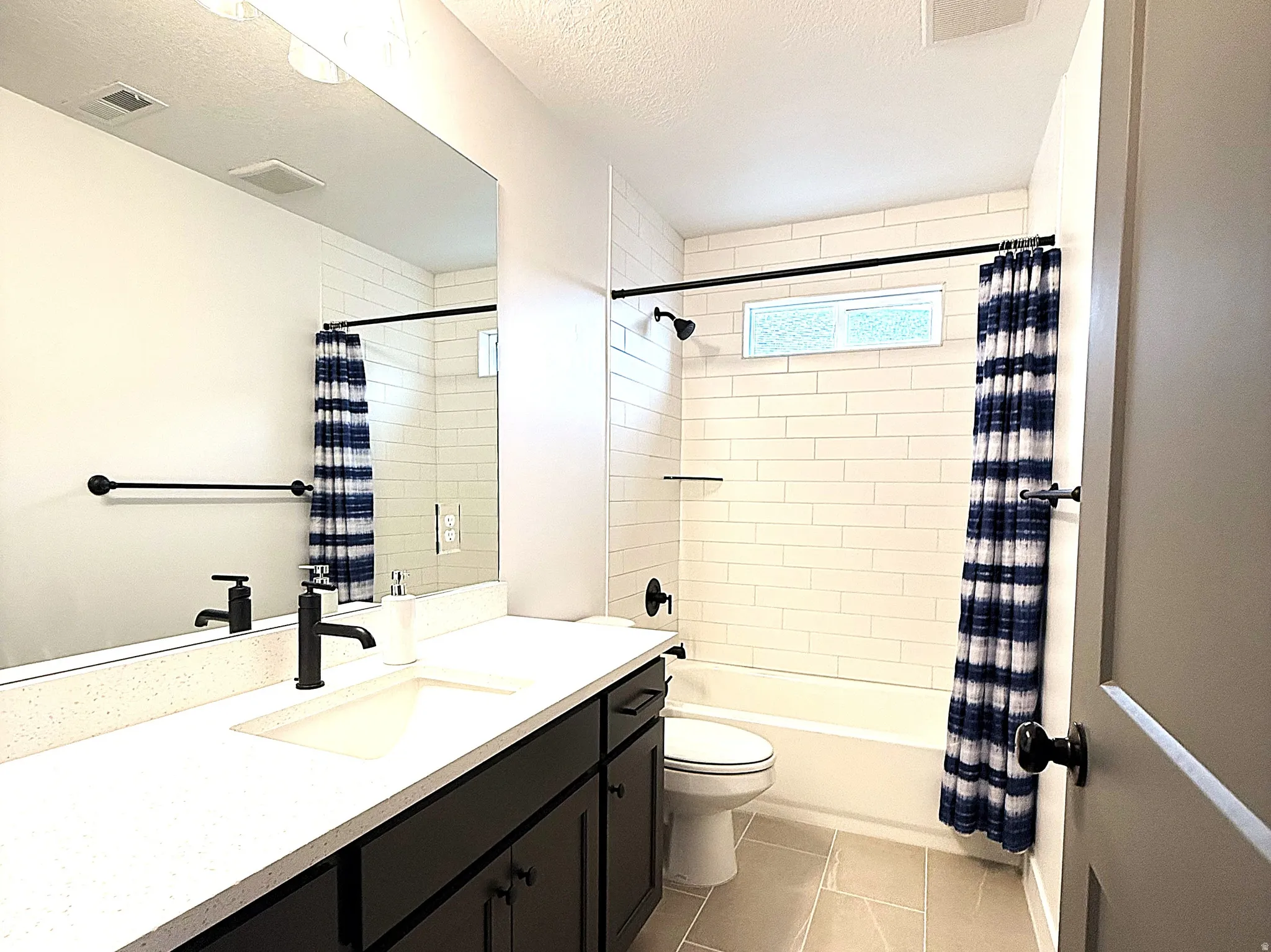 Full bath featuring vanity, a textured ceiling, and shower / bathtub combination with curtain