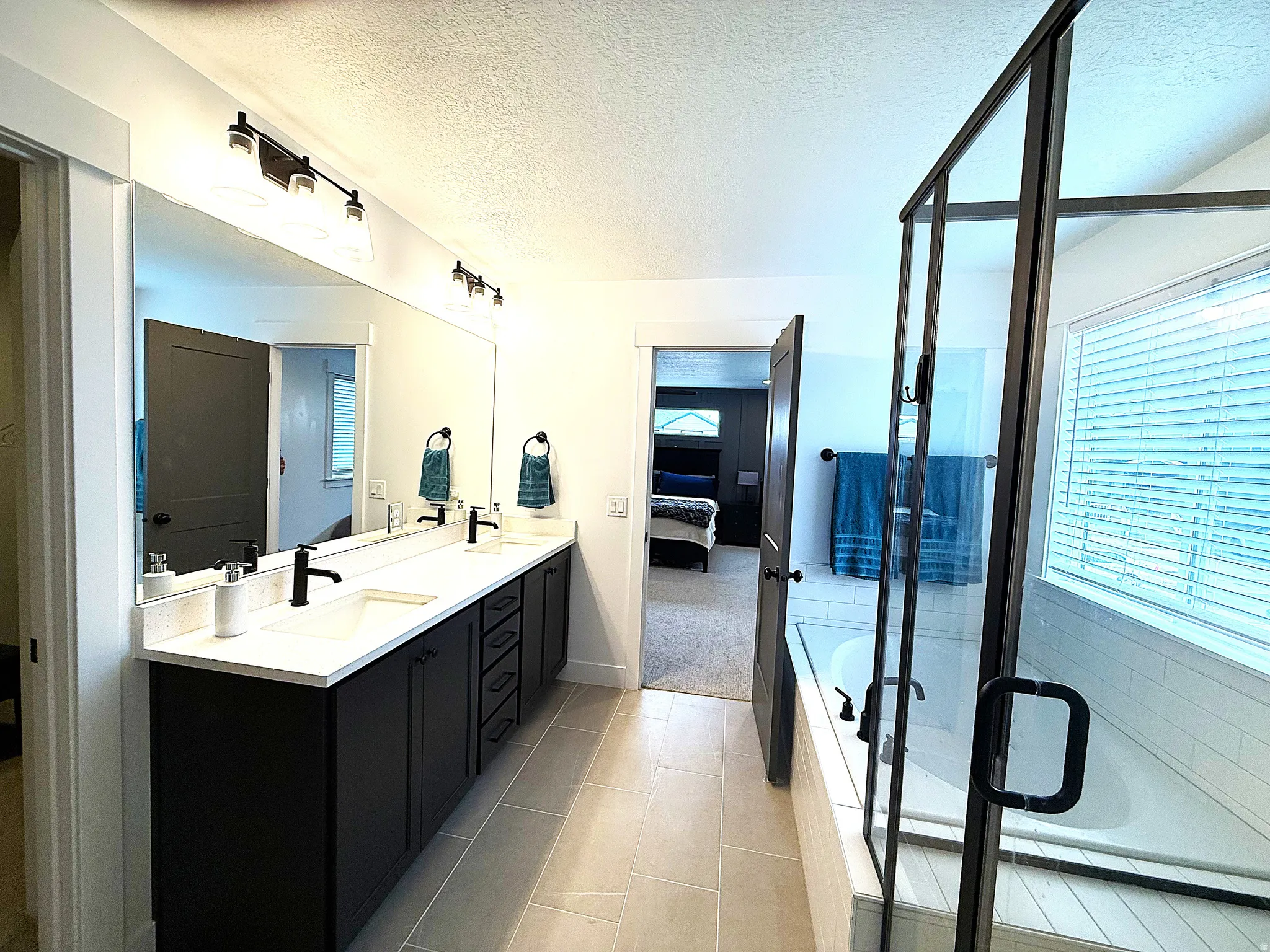 Full bathroom with a textured ceiling, double vanity, a garden tub, a shower stall, and ensuite bathroom