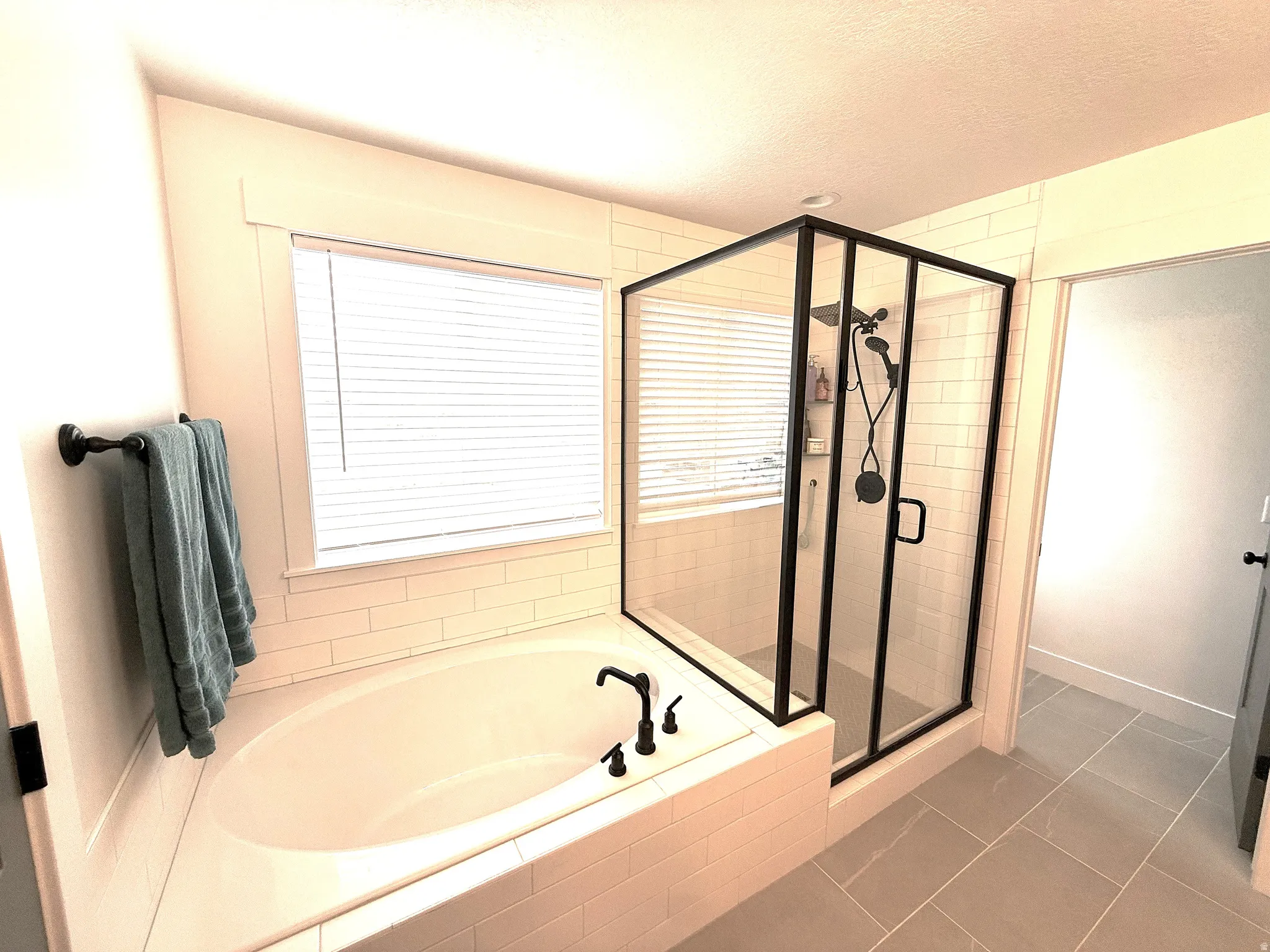 Full bathroom featuring a stall shower, a bath, tile patterned flooring, and a textured ceiling
