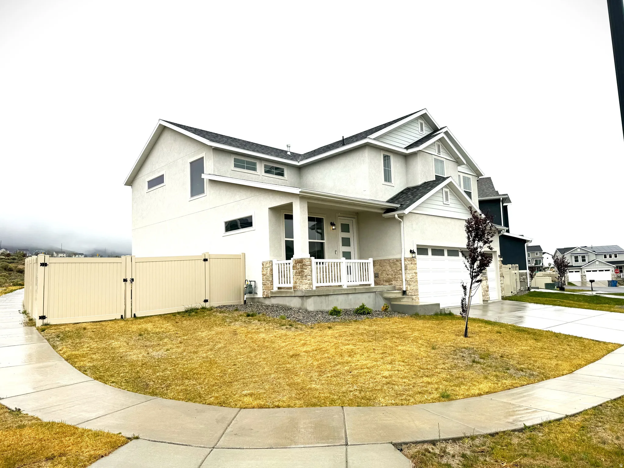 View of front of home with covered porch, stucco siding, a gate, a garage, and driveway