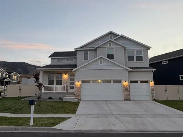 Two-story residence featuring a stucco exterior with stone accents and a covered front porch