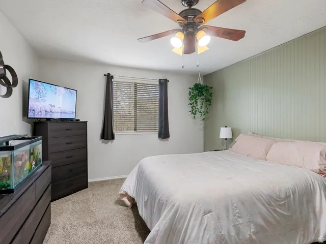 Bedroom with light carpet, ceiling fan, and a textured ceiling