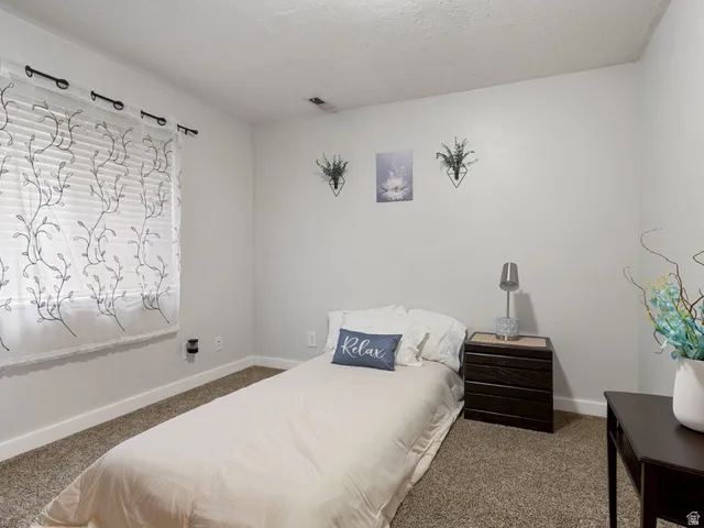 Carpeted bedroom featuring baseboards and a textured ceiling