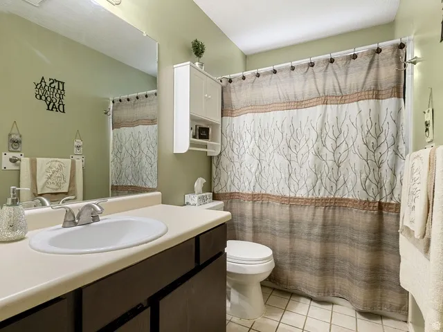 Full bath with vanity, curtained shower, and light tile patterned flooring