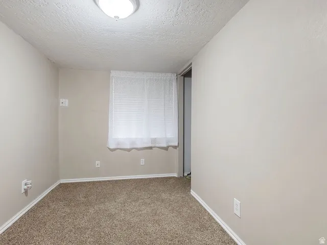 Carpeted spare room with baseboards and a textured ceiling
