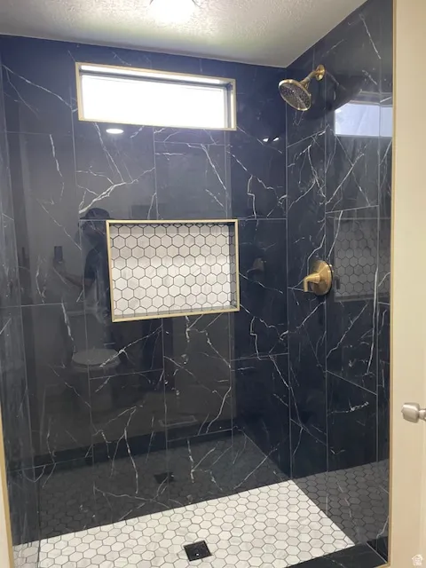 Primary Bathroom with a textured ceiling and a marble finish shower