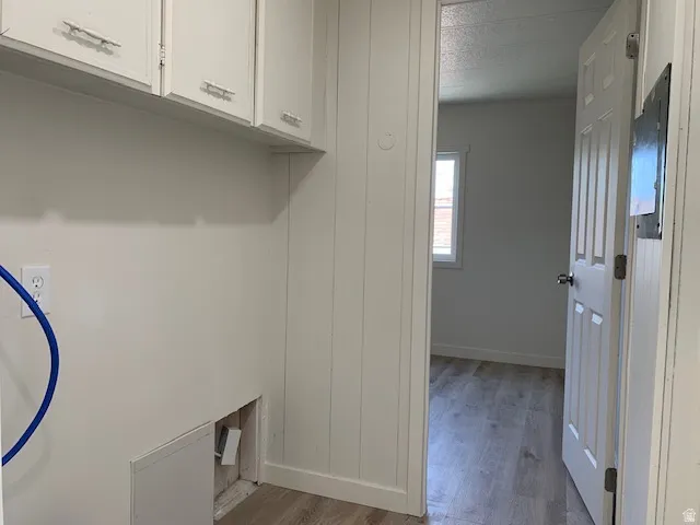 Laundry area featuring cabinet space and light wood-style floors