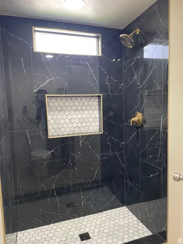 Primary Bathroom with a textured ceiling and a marble finish shower