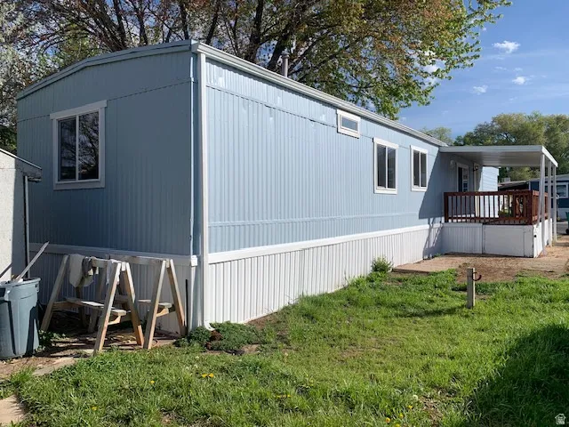 View of home's exterior featuring a lawn and a wooden deck