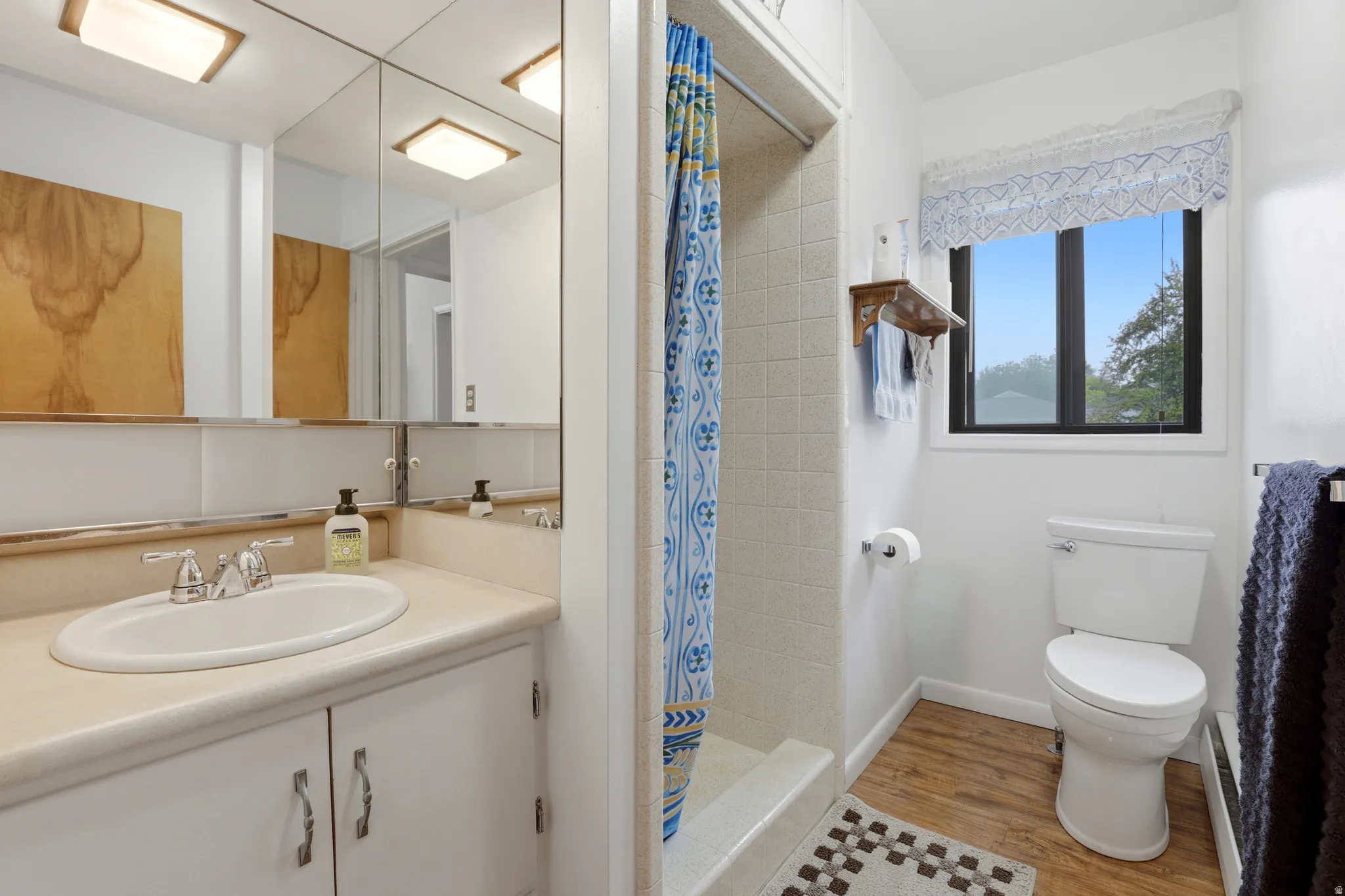 Full bathroom featuring vanity, a shower stall, and light wood-style floors
