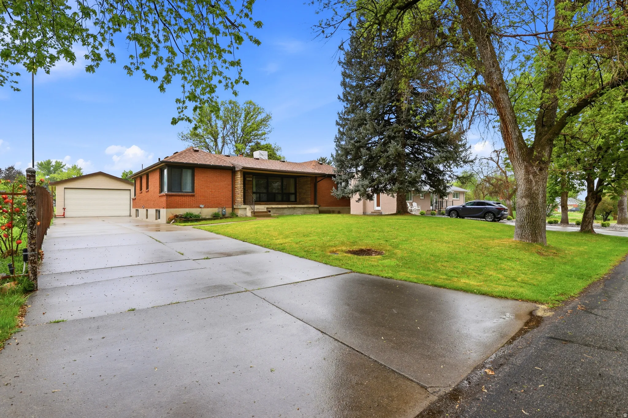 Ranch-style house featuring an outbuilding, brick siding, a garage, a chimney, and a front yard