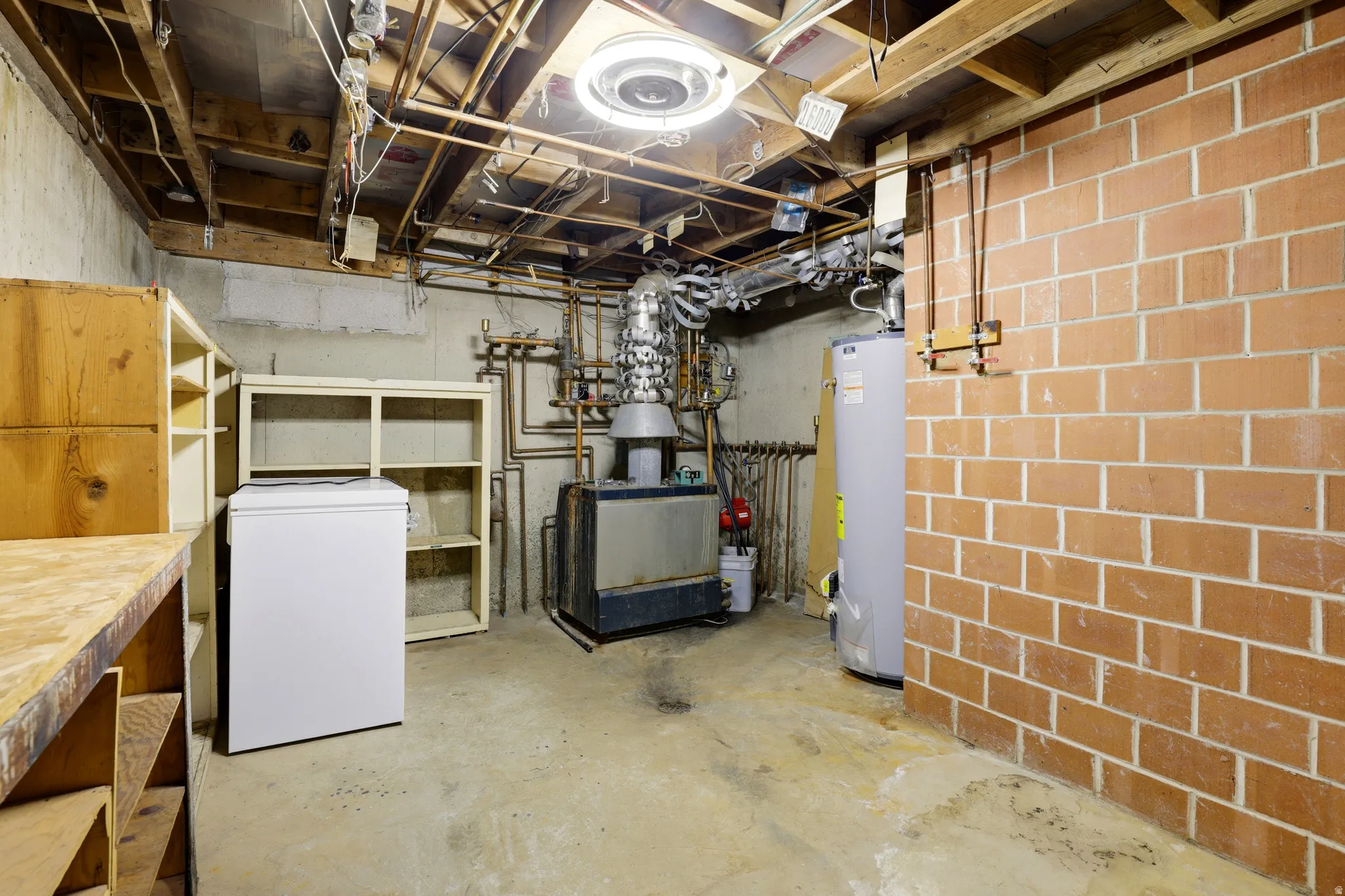 Unfinished below grade area with white refrigerator and water heater