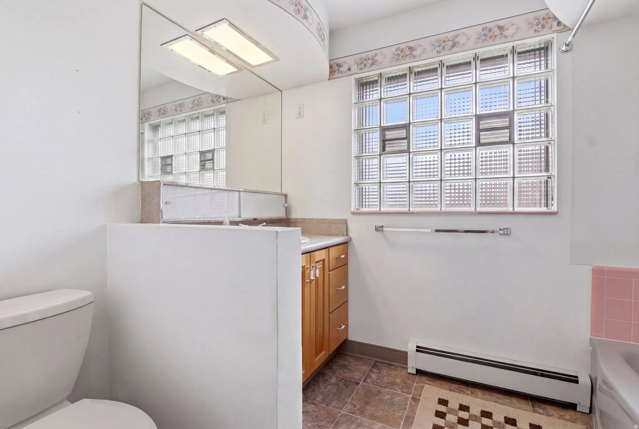 Full bathroom with vanity, baseboard heating, and a tub to relax in