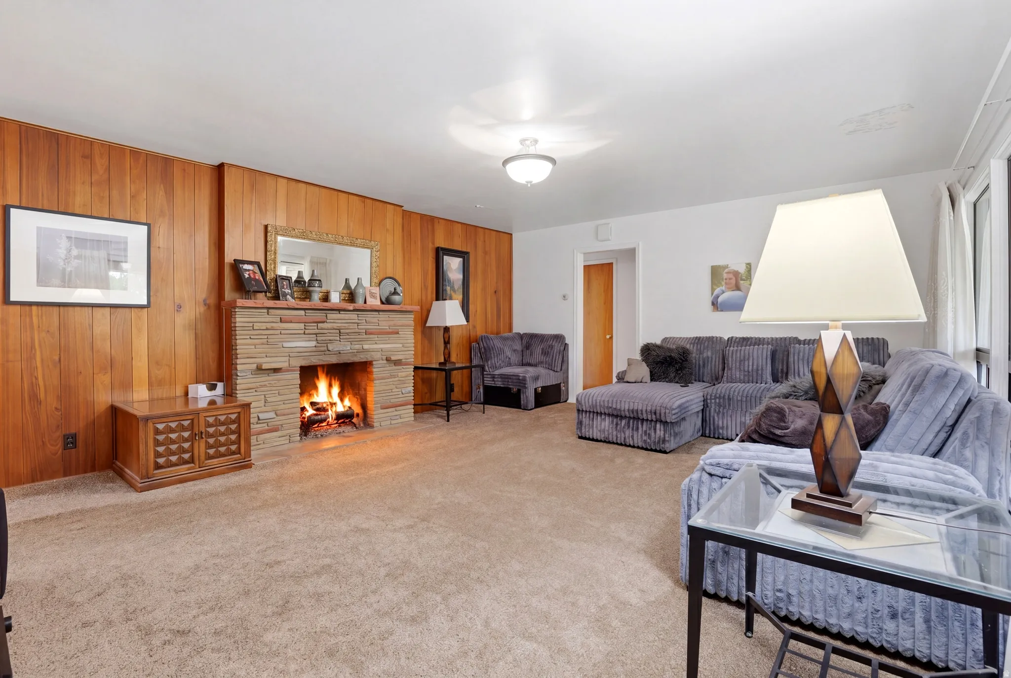 Carpeted living area with a stone fireplace and wood walls