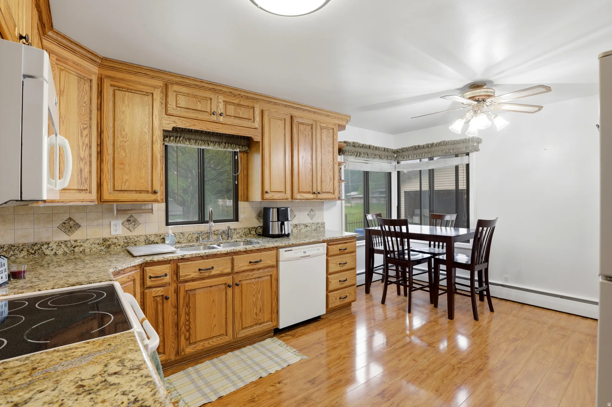 Kitchen with light stone countertops, a ceiling fan, decorative backsplash, and plenty of natural light
