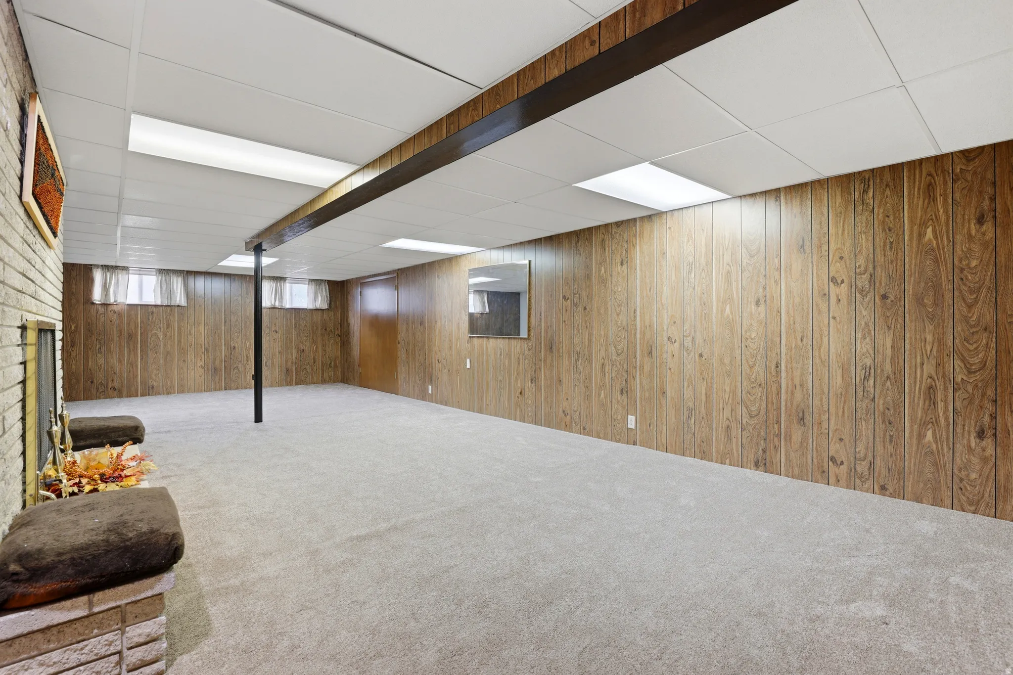 Below grade area featuring a drop ceiling, carpet floors, and wooden walls