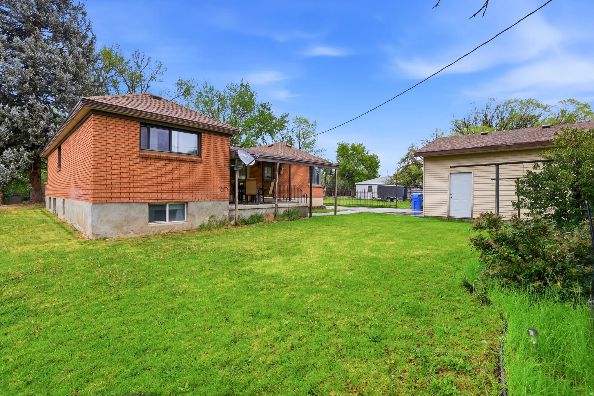 Back of house with brick siding, a lawn, and an outdoor structure