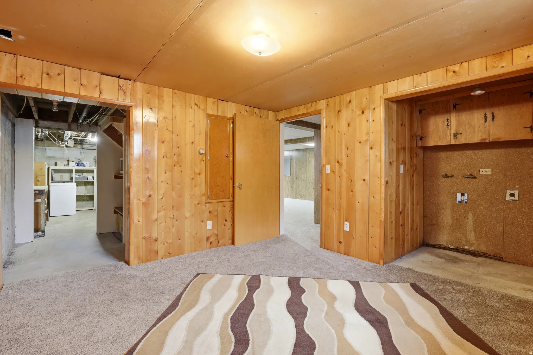 Unfurnished bedroom with wood walls and washer / dryer