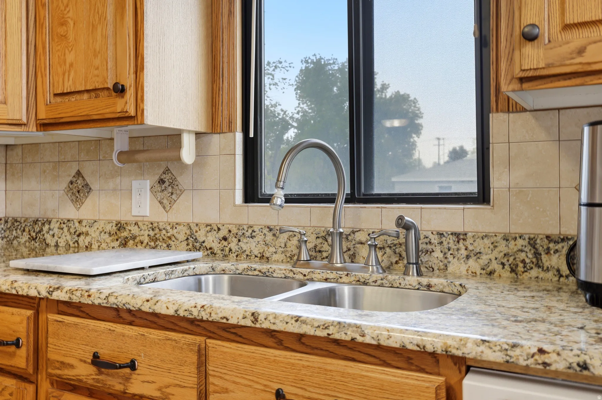 Kitchen with wood finish cabinetry, light stone countertops, and decorative backsplash