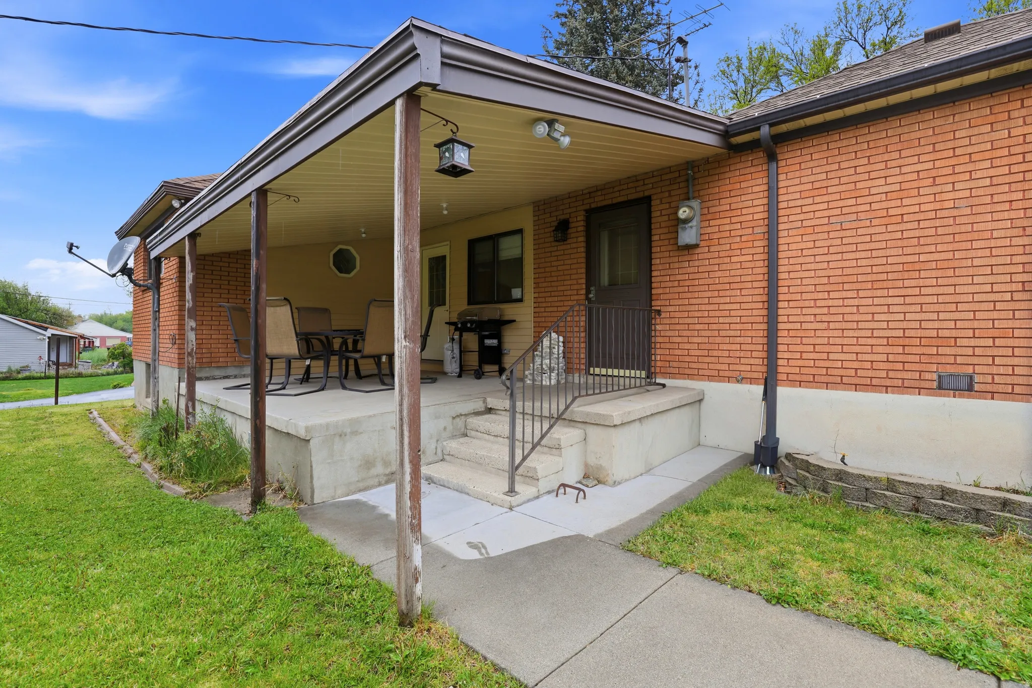 View of front of house featuring covered porch, brick siding, and a front yard