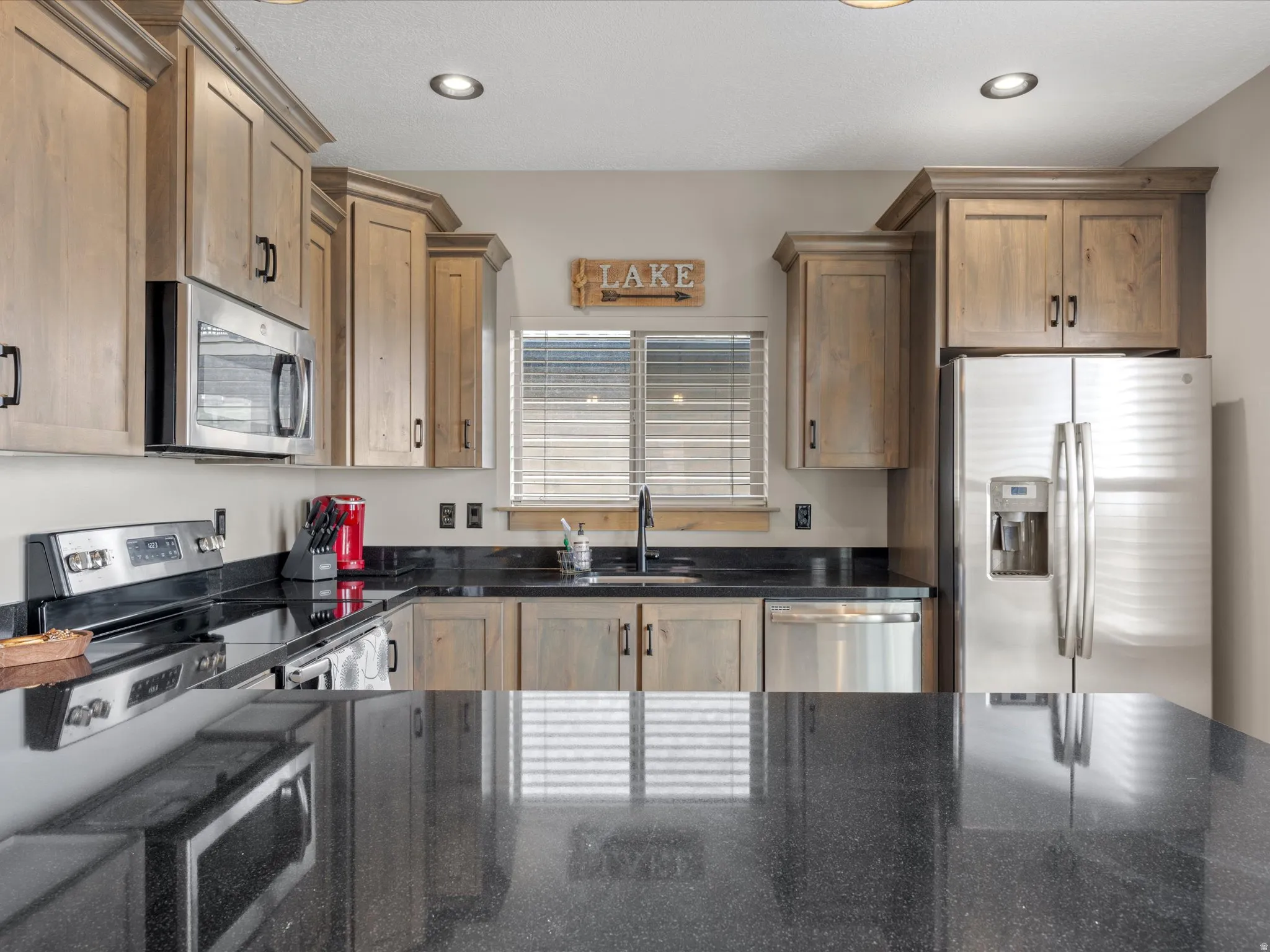 Kitchen featuring stainless steel appliances, dark stone countertops, and recessed lighting