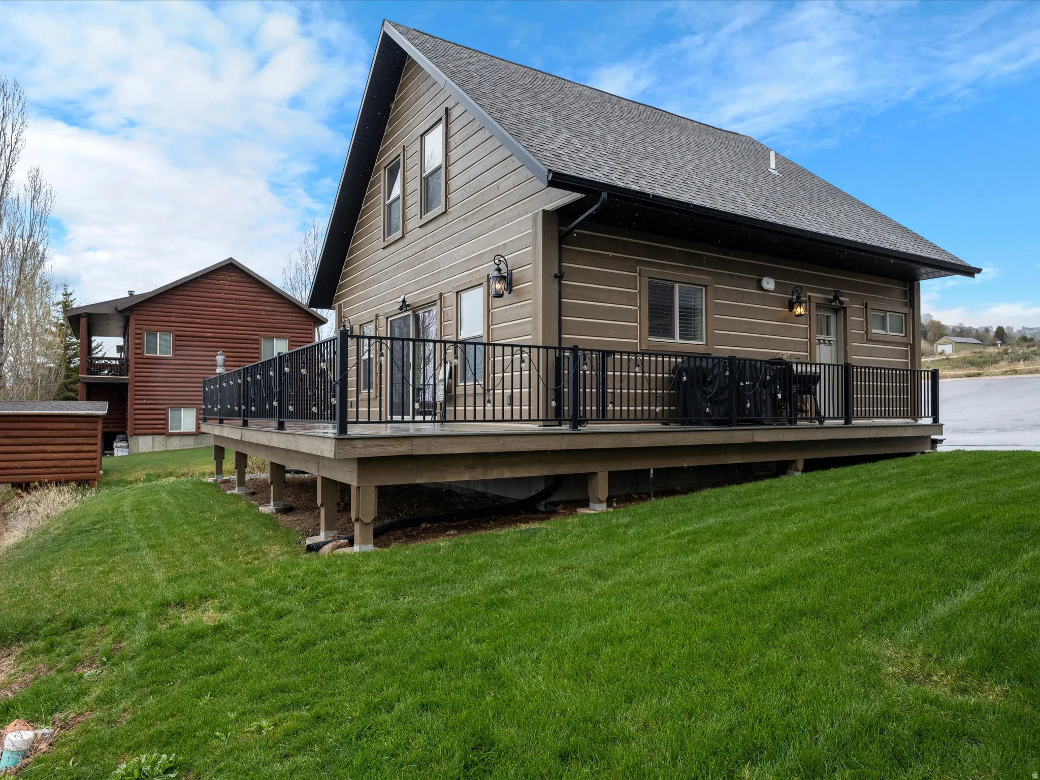 Rear view of property featuring a yard, a wooden deck, and a shingled roof