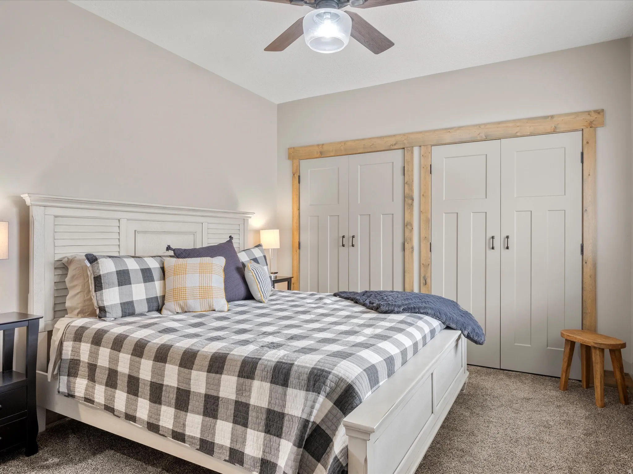 Carpeted bedroom with a ceiling fan and two closets