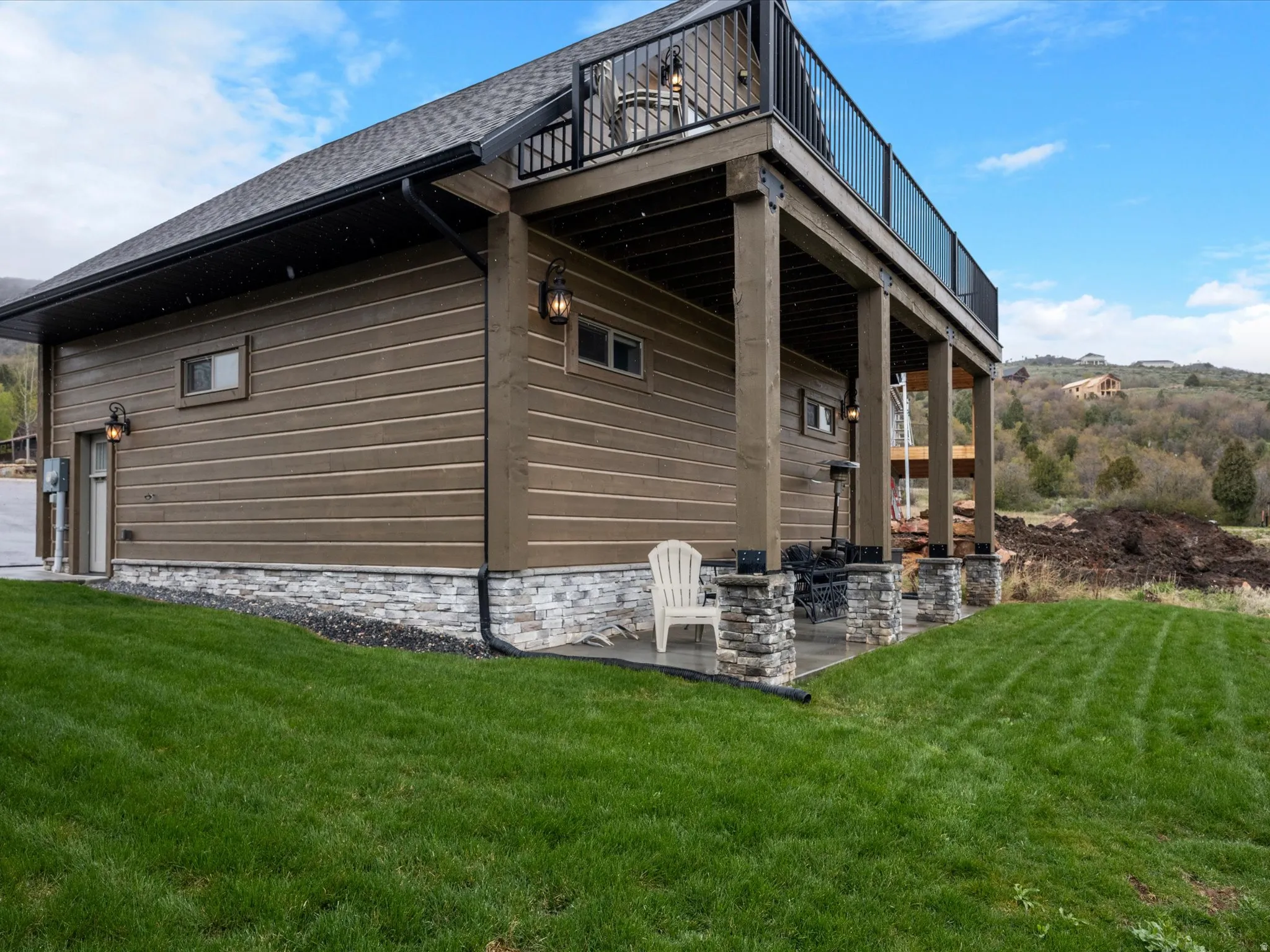 View of side of home with a lawn, roof with shingles, and a patio