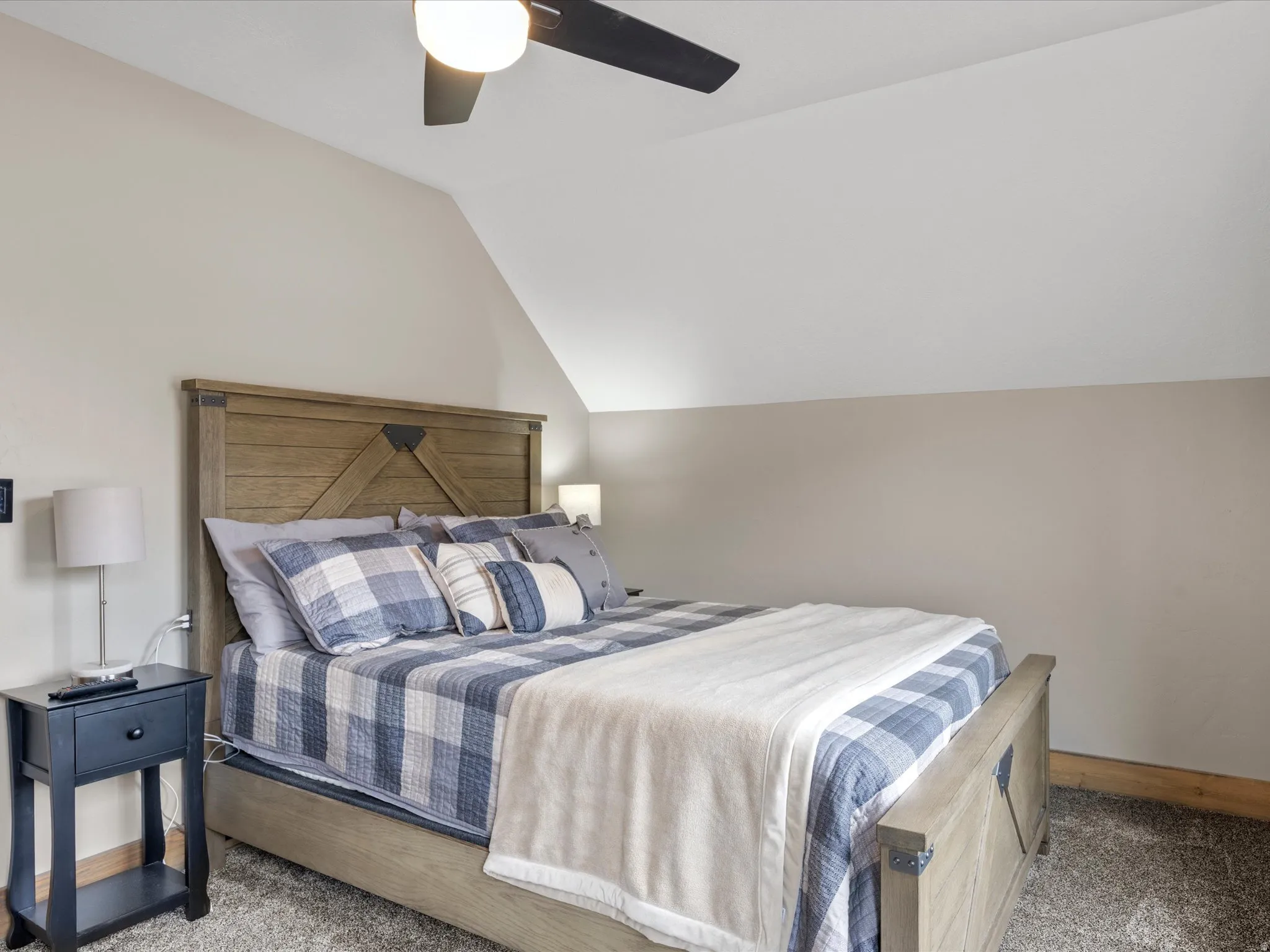 Carpeted bedroom with vaulted ceiling and a ceiling fan