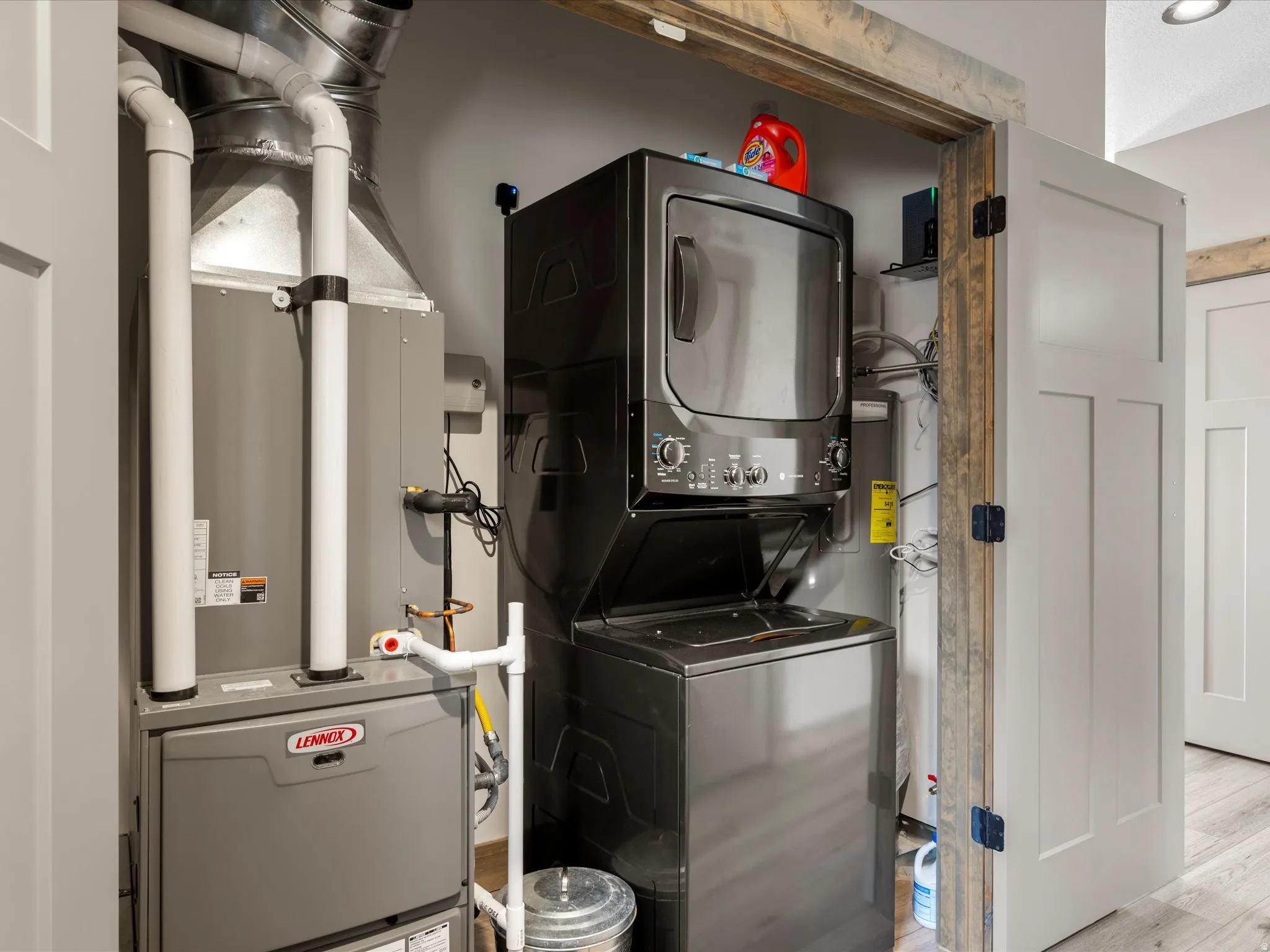Laundry area featuring heating unit, stacked washer and dryer, and light wood finished floors