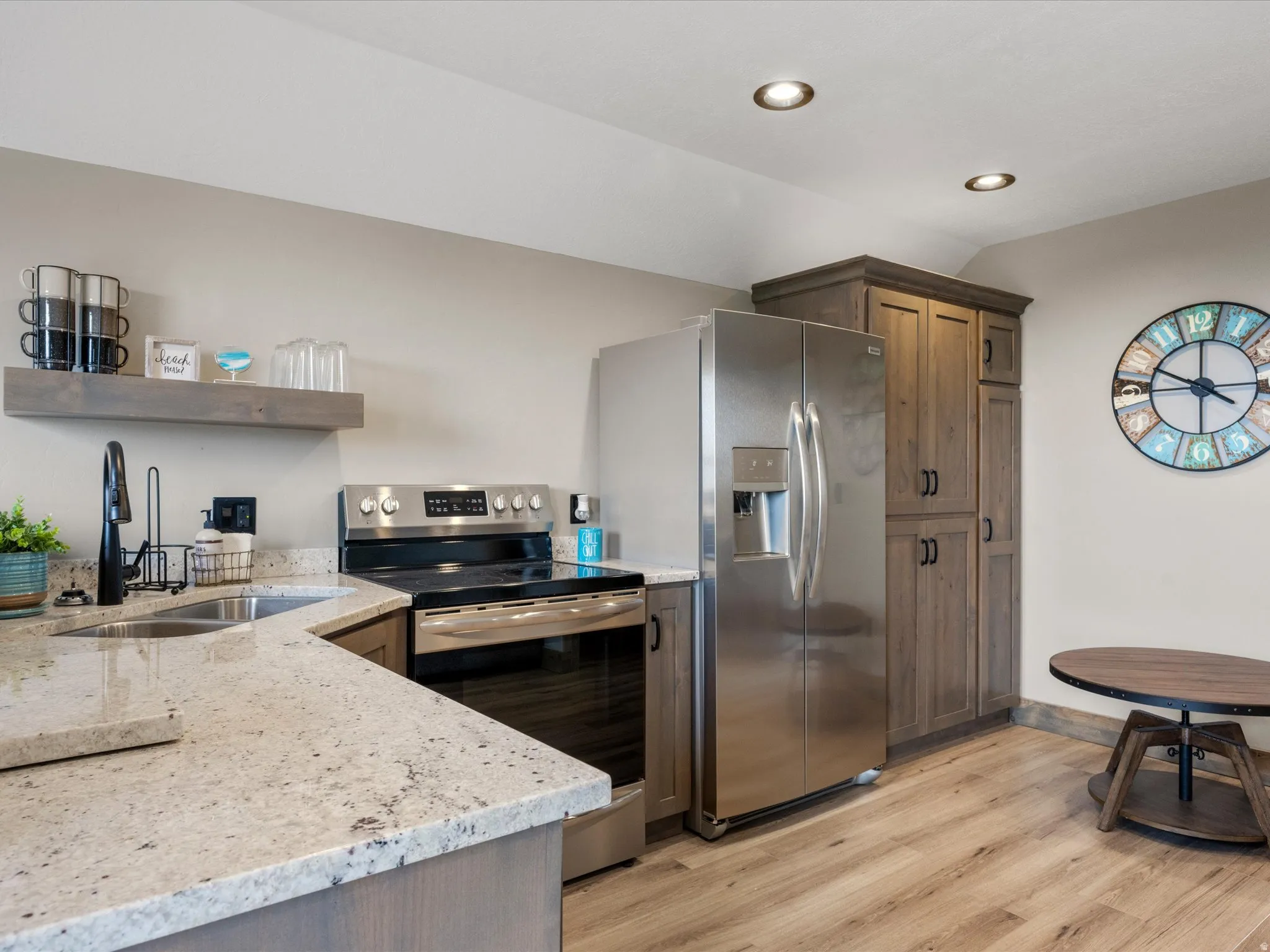 Kitchen with light stone countertops, stainless steel appliances, light wood finished floors, vaulted ceiling, and recessed lighting