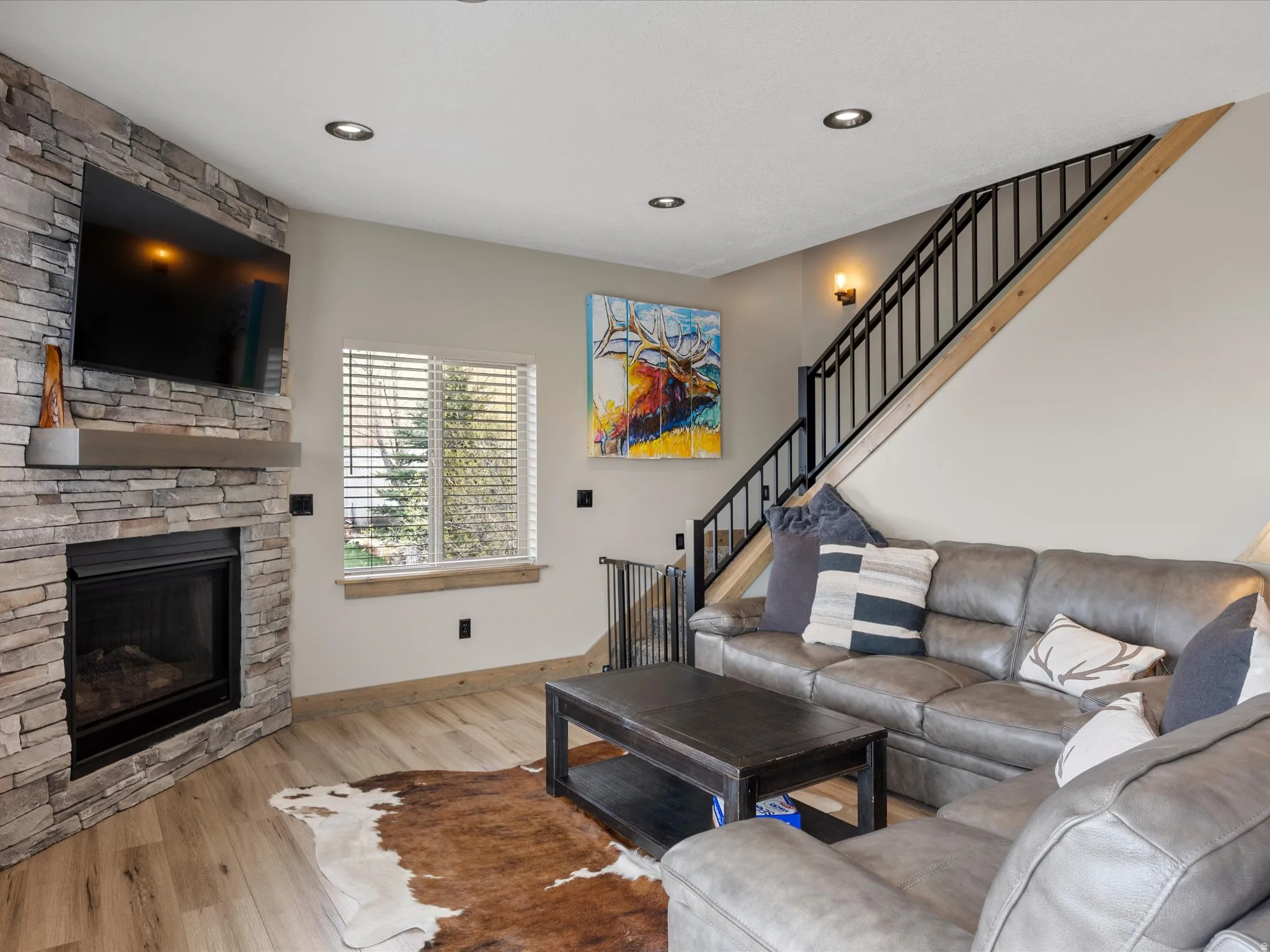 Living room with light wood-type flooring and a stone fireplace