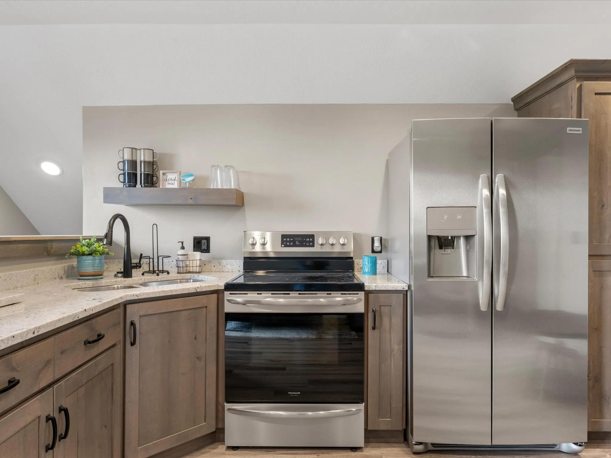 Kitchen with stainless steel appliances, light stone counters, open shelves, and wood finish cabinetry