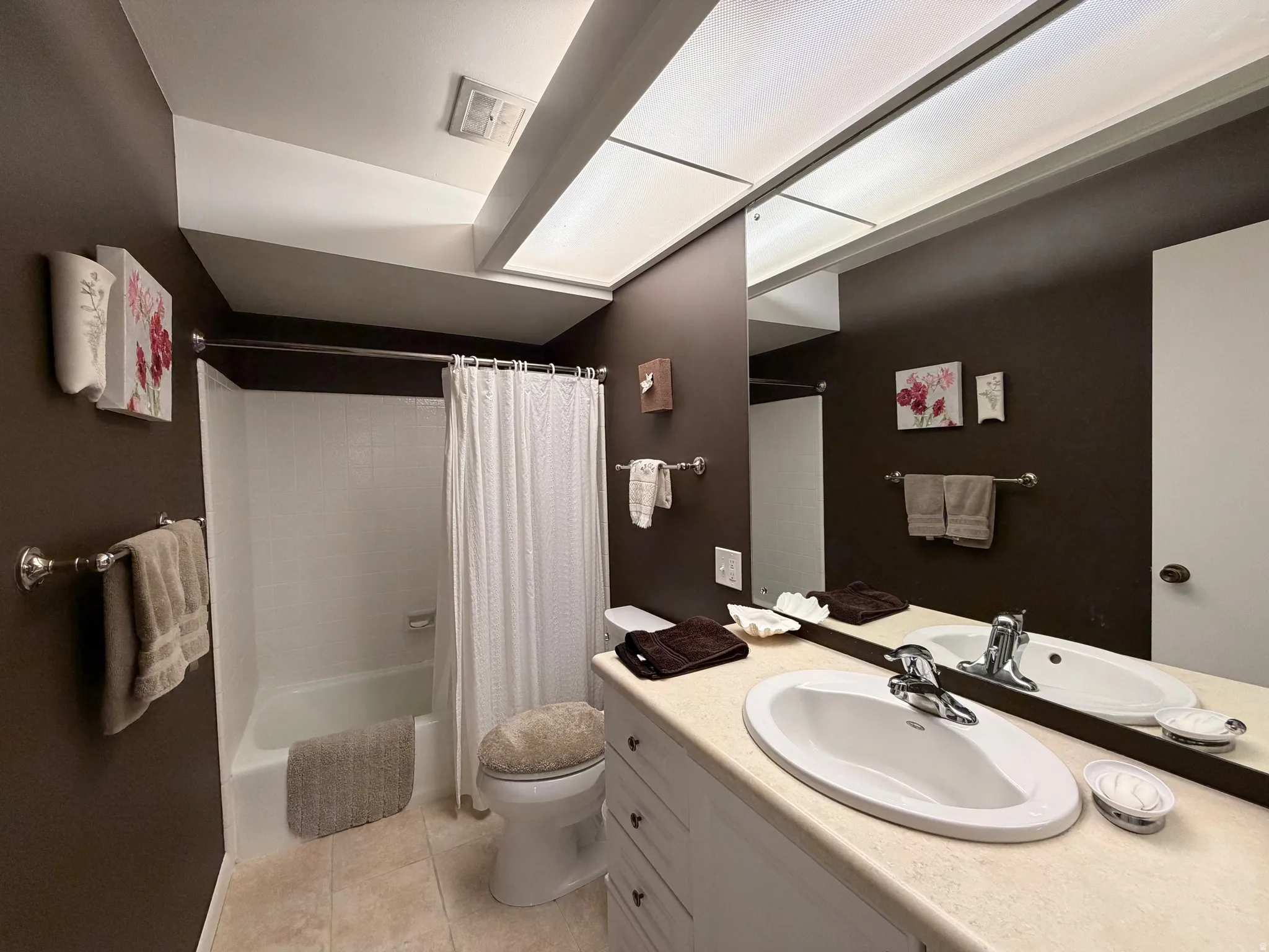 Bathroom featuring vanity, shower / bath combination with curtain, and light tile patterned floors
