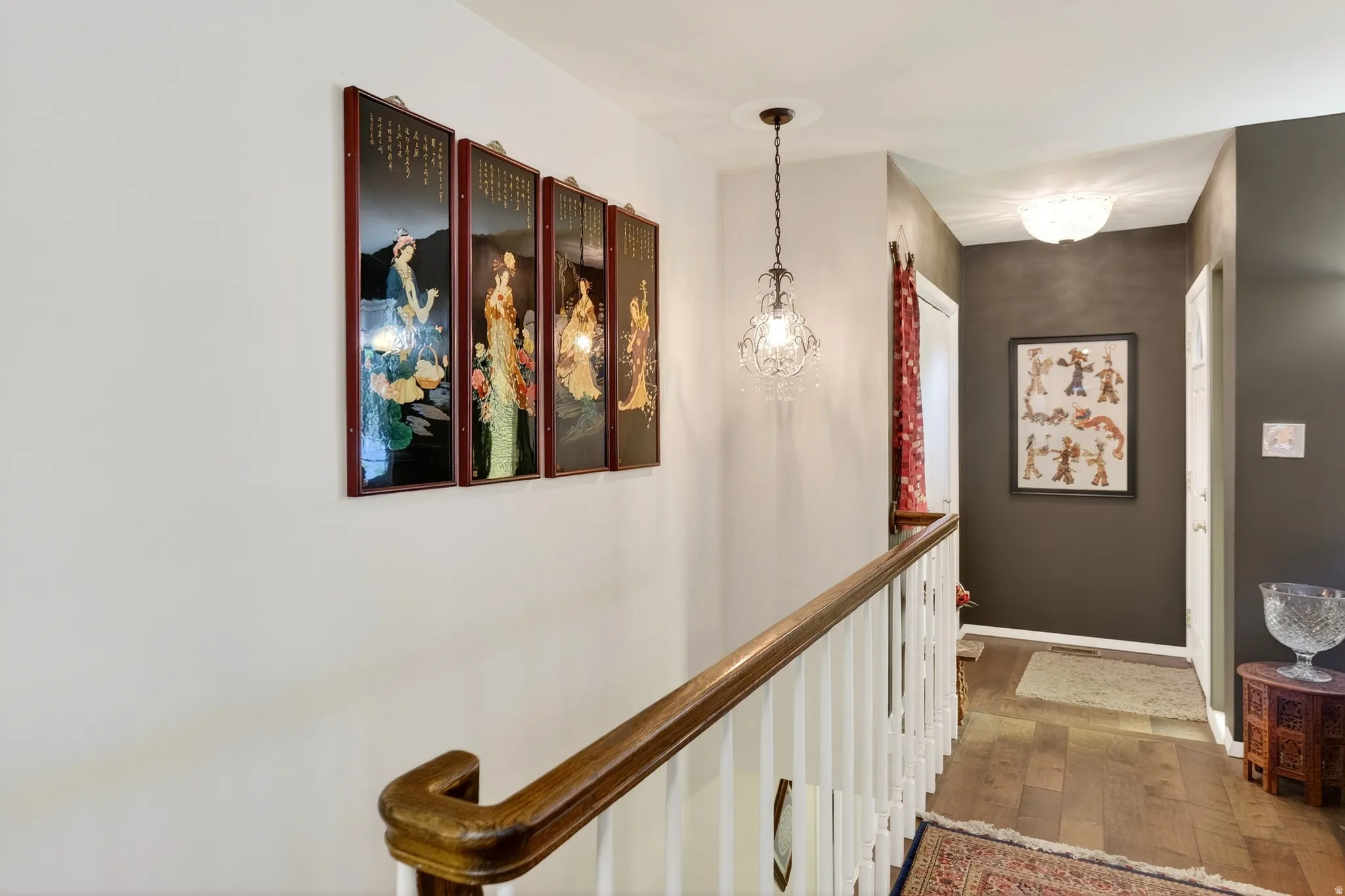 Corridor with wood-type flooring, an upstairs landing, and hanging lights