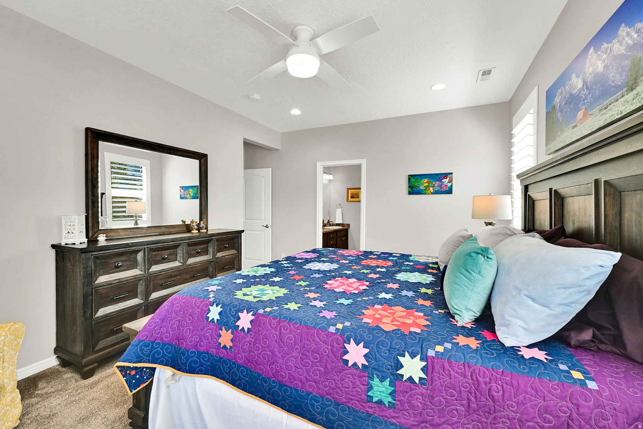 Large primary bedroom featuring ceiling fan, ensuite bath, light carpet, and recessed lighting