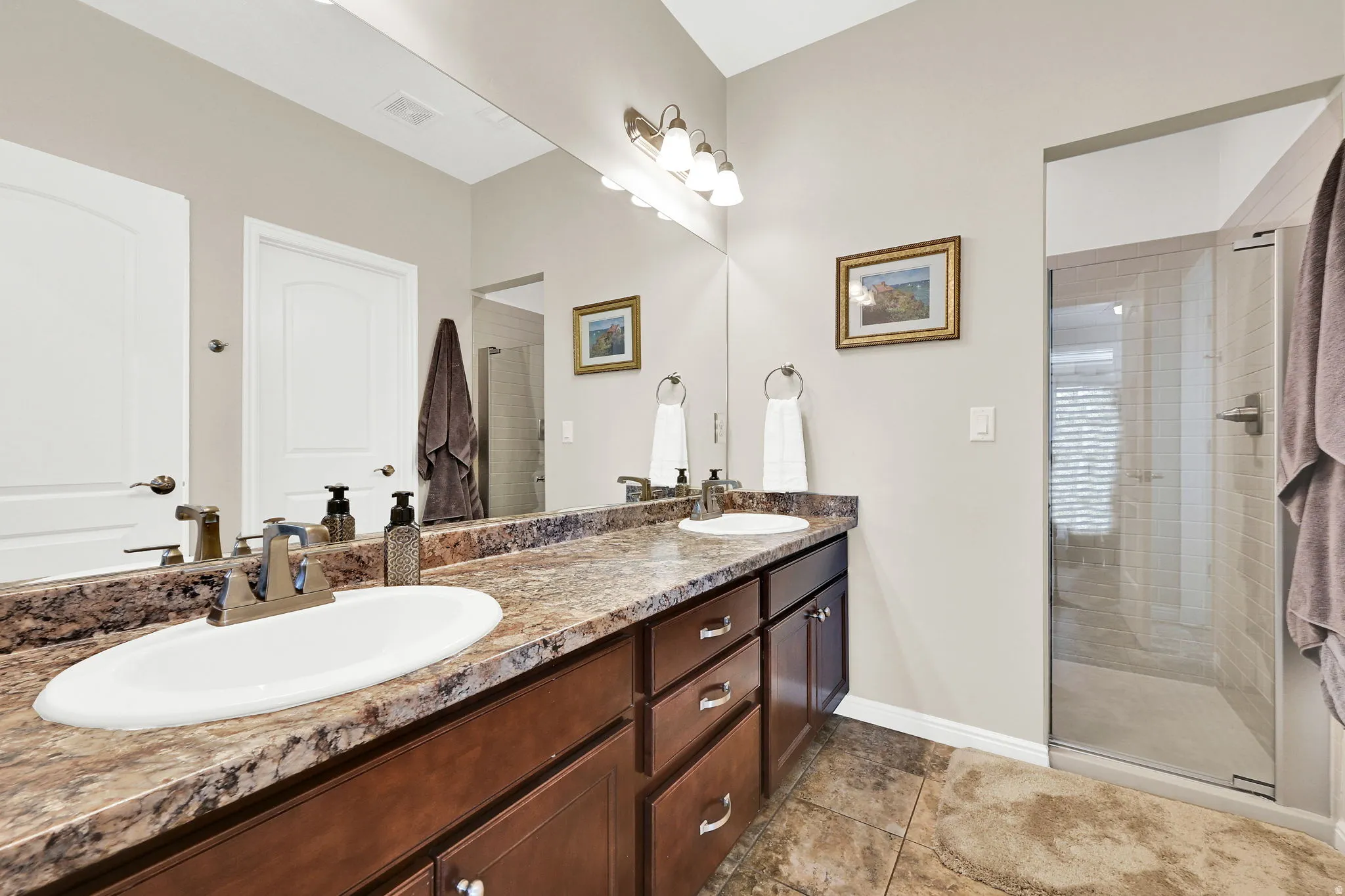 Primary bathroom with a shower stall, and double vanity.
