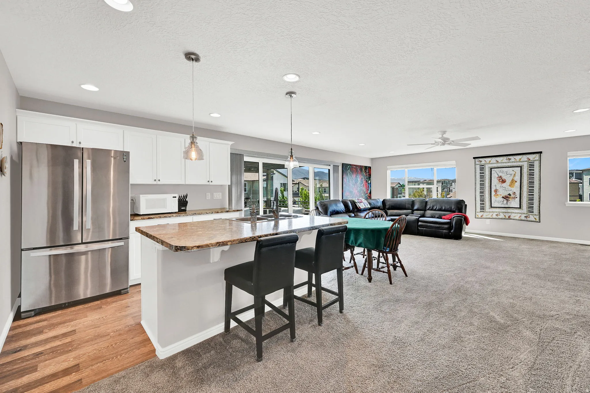 2nd partial kitchen featuring freestanding refrigerator, white cabinetry, a kitchen island with sink, a breakfast bar area, and open floor plan with views out on the deck
