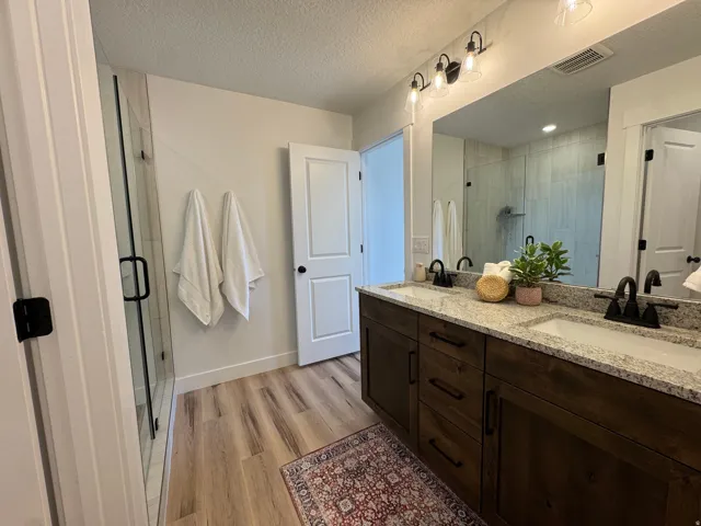 Double vanity featuring dark wood-finish cabinetry, light-toned countertops, and dual undermount sinks with matte black fixtures