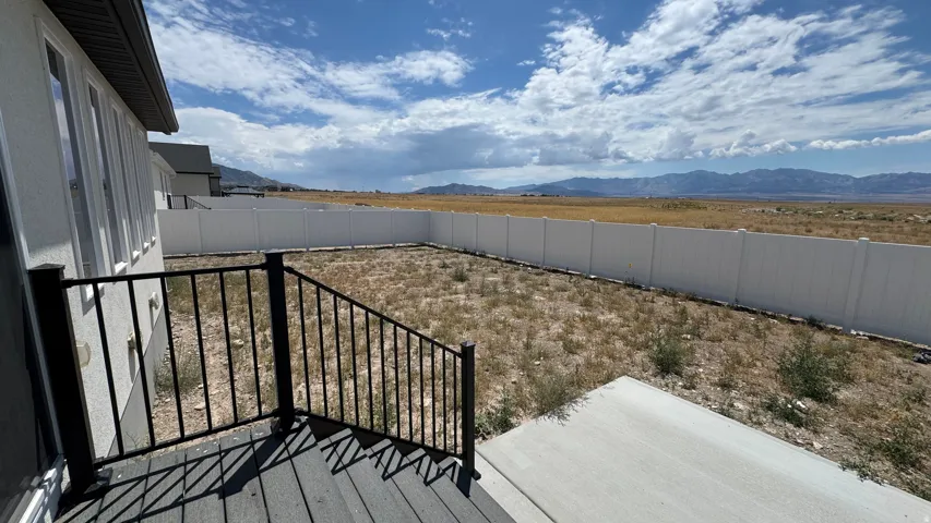 Rear exterior featuring a composite deck, black metal railing, and a concrete patio